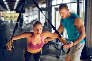 Trainer studying for a fitness certification, surrounded by textbooks and workout plans